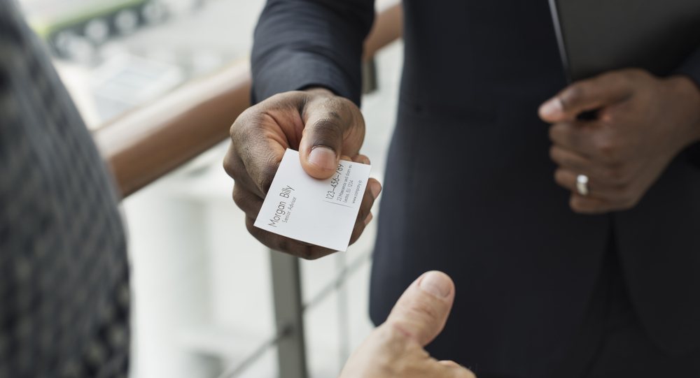 One person handing a business card to another