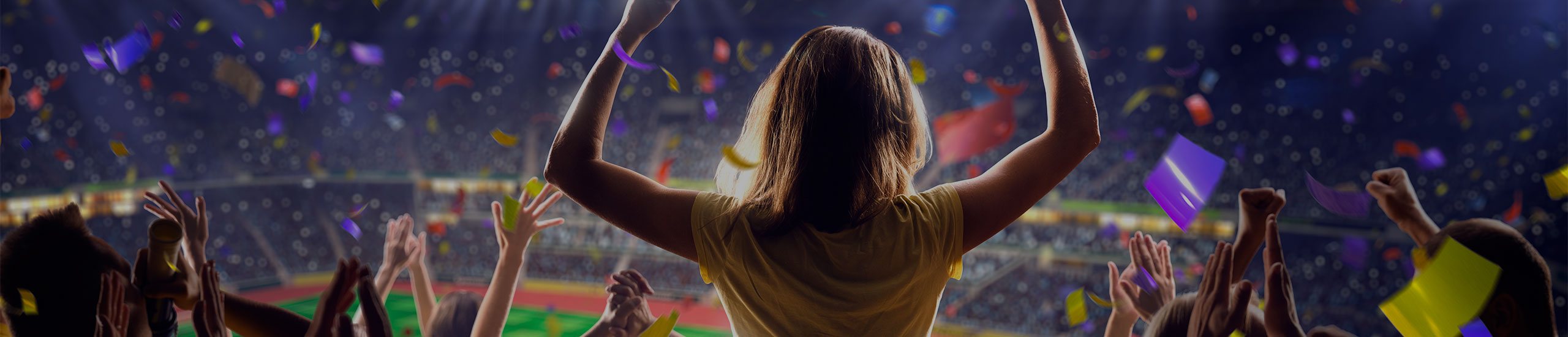 A crowd celebrating in a packed stadium as confetti falls